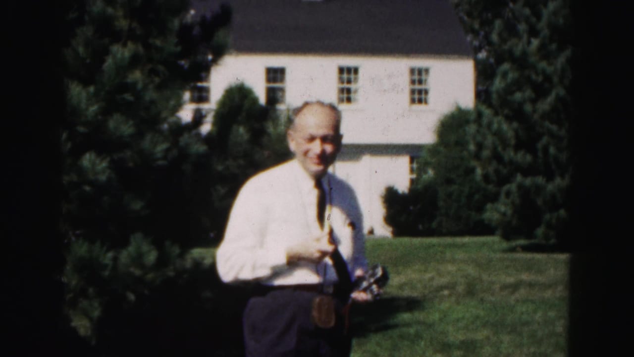 In 1963 Hagerstown, Maryland home-movie footage, a man in a white shirt and tie smiles while standing on a lawn before a white house.