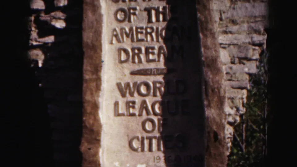 A closer lower view shows the World League of Cities wording, heavy shadow, and chipped stone around the plaque in the 1963 Maryland footage.
