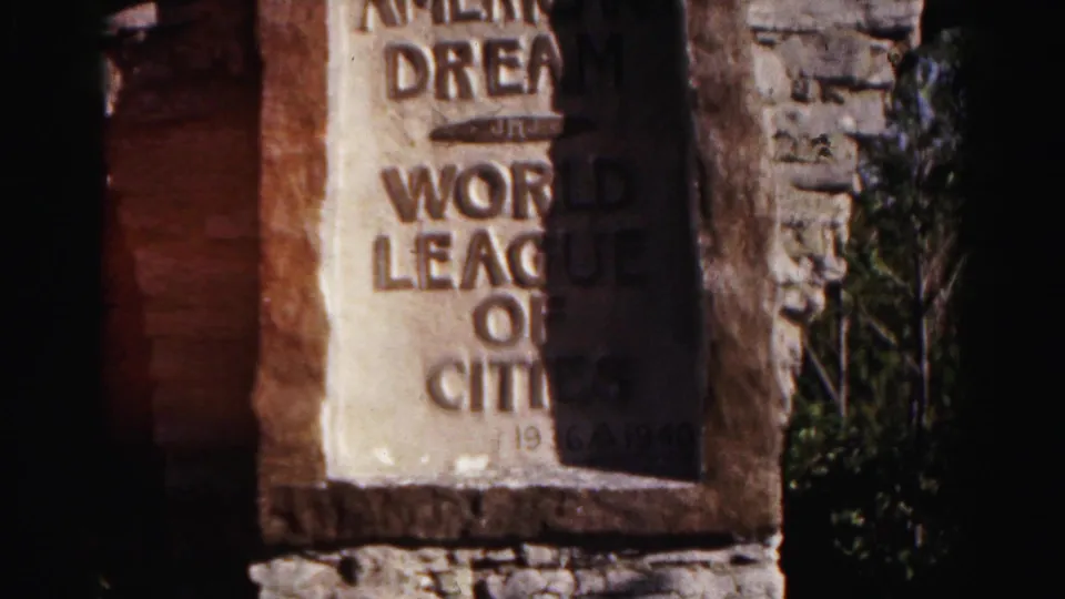 The final frame shows most of the plaque in the stone wall, including the Chapel of the American Dream and World League of Cities inscription.