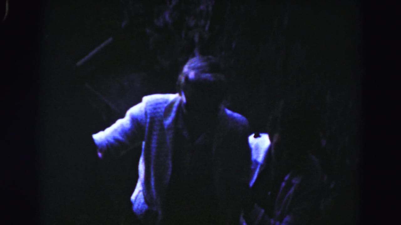 Man in a light jacket climbs stairs beside another partly obscured figure.