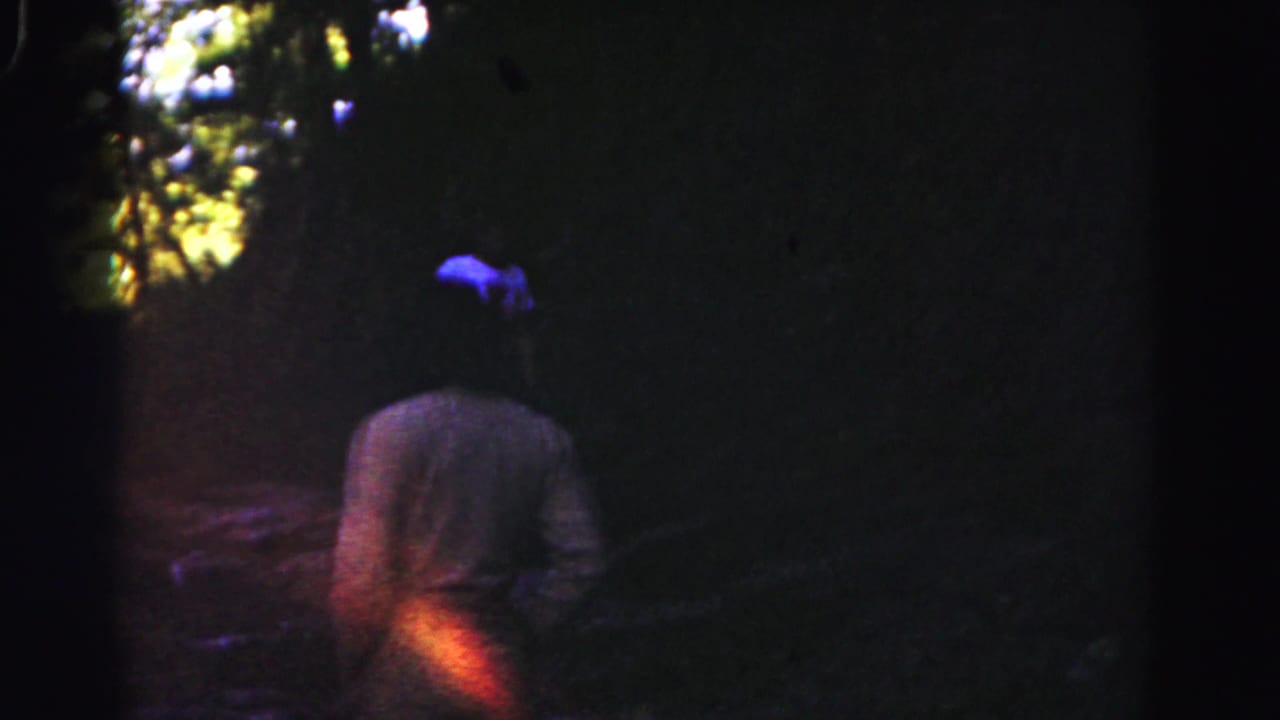 A dim 1963 Hagerstown woods frame shows one person walking away while a blue-shirted figure appears farther ahead.