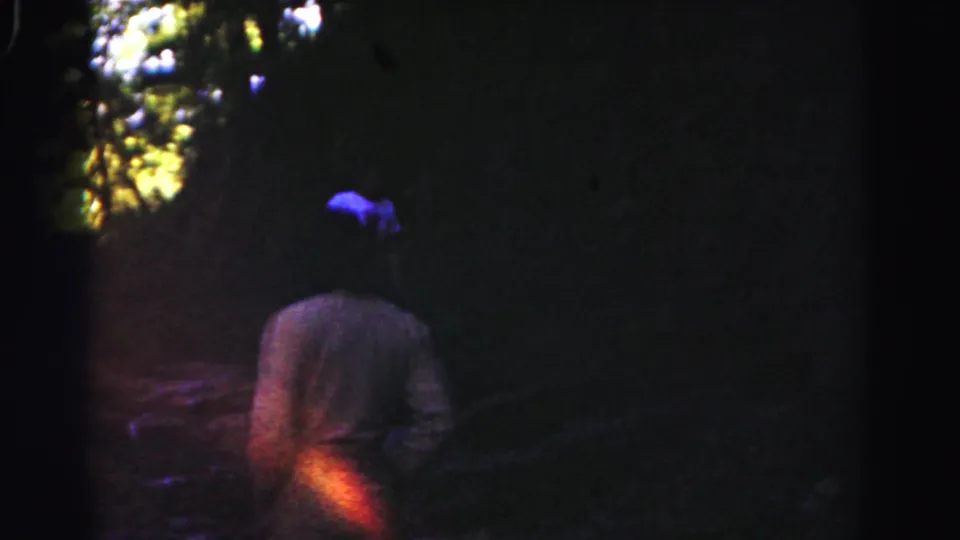 A dim 1963 Hagerstown woods frame shows one person walking away while a blue-shirted figure appears farther ahead.