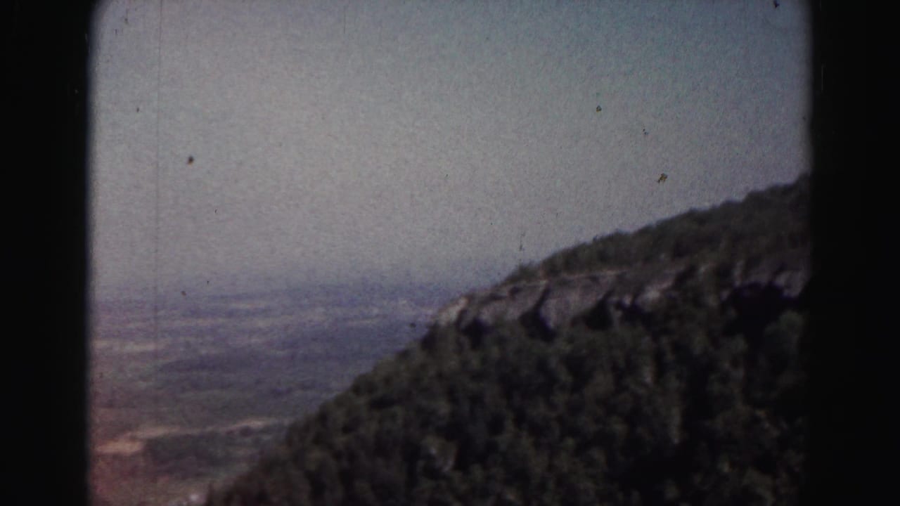 1963 Hagerstown-area 8mm view of a distant valley and wooded hillside through a car window.