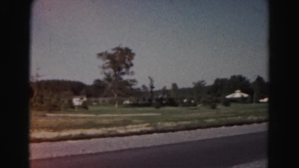 1963 Hagerstown-area suburban roadside view with open grass, scattered trees, and low distant buildings.