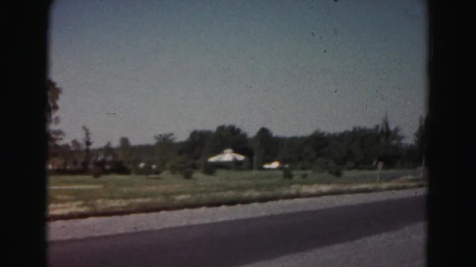 1963 Hagerstown-area roadside scene showing open grass, trees, and low white structures beyond the road.