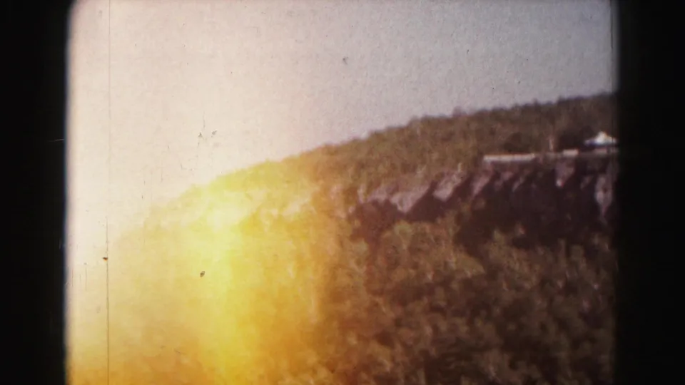 1963 Hagerstown-area 8mm frame showing a wooded ridge and hazy valley view, partly obscured by a bright film light leak.