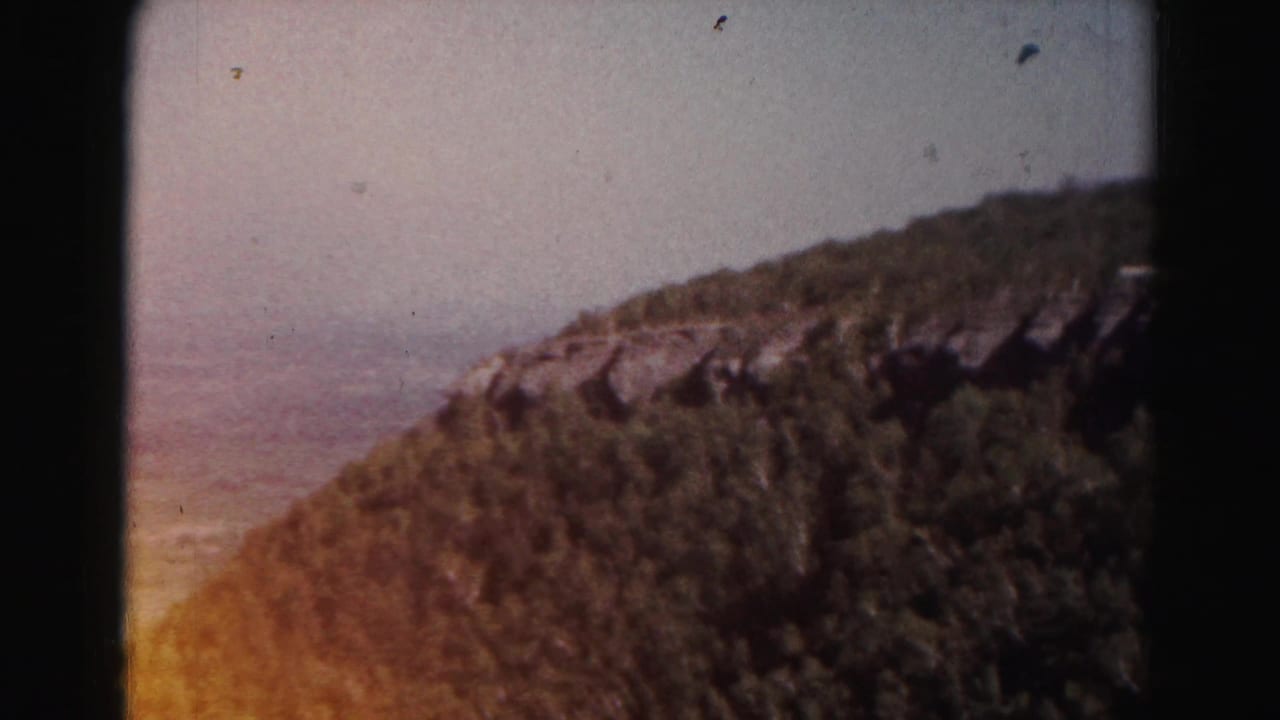 Forested hillside with a hazy valley beyond and dark film gate edge visible.