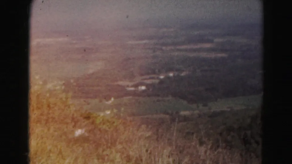 1963 Hagerstown-area 8mm frame showing a broad valley, patchy farmland, and dry brush from a high scenic viewpoint.