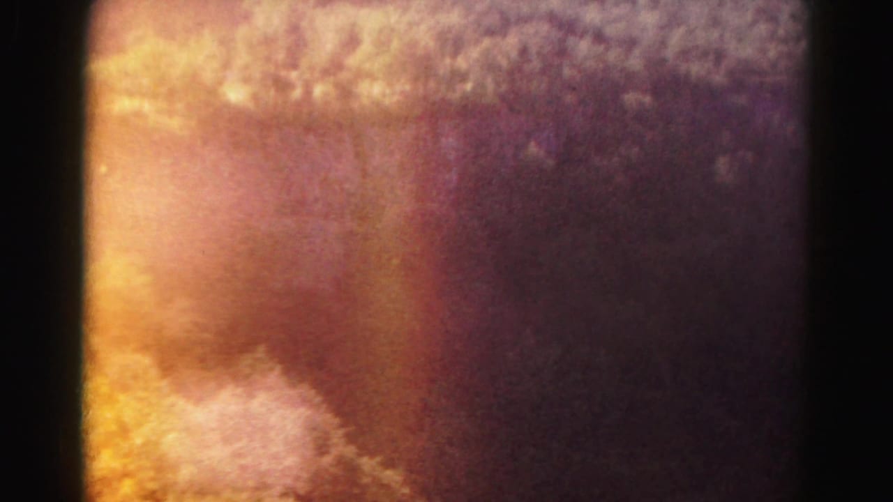 Warm overexposed sky and blurred forested terrain with dark 8mm frame edges.