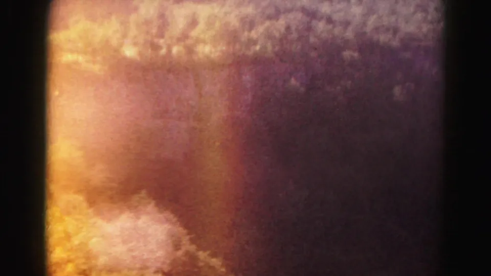 1963 8mm home-movie frame from Hagerstown metadata showing warm sky exposure and soft aerial landscape texture.