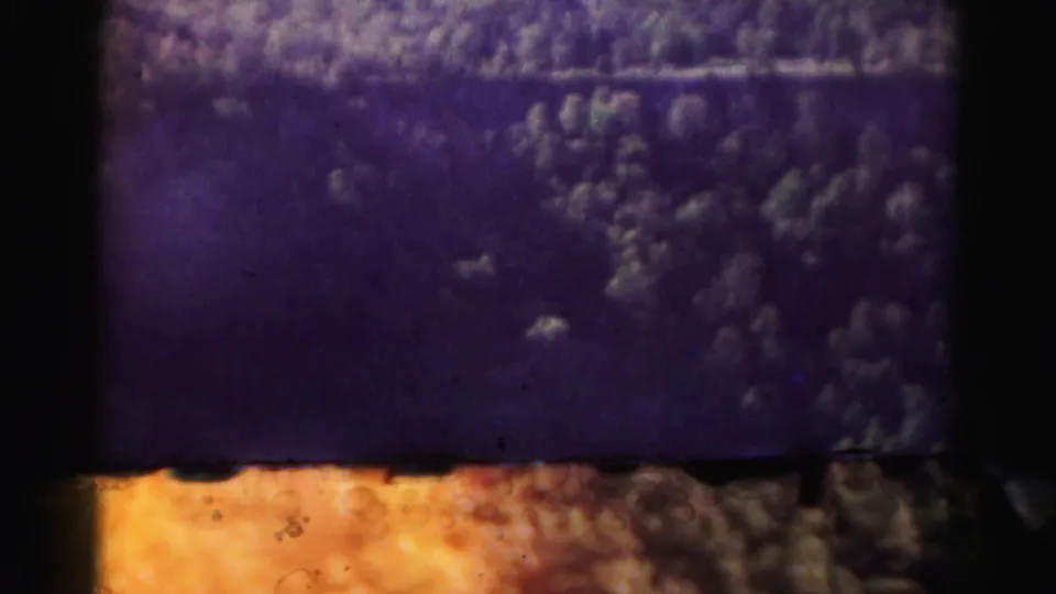 Color-shifted 8mm aerial landscape frame from Hagerstown metadata with wooded terrain, pale patches, and visible film edge.