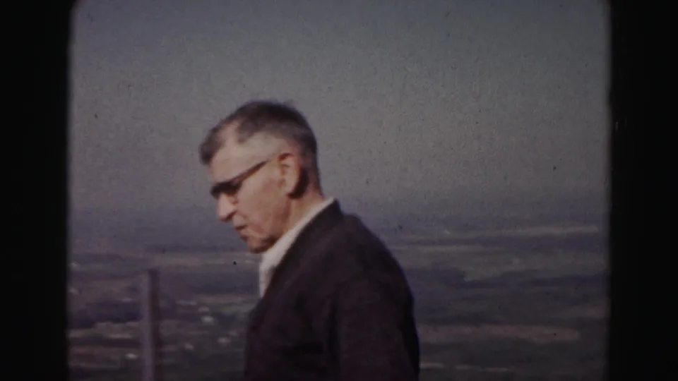 The man appears in profile at the Hagerstown-area overlook, with a railing post and distant terrain visible in soft 8mm color.