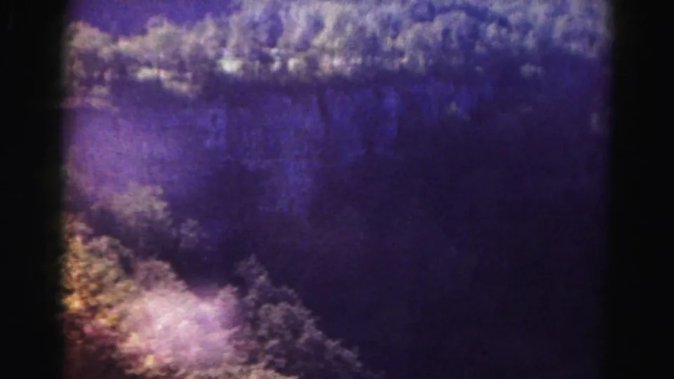 The closing frame shows a purple-toned landscape view in the 1963 home movie, with heavy color shift, grain, and soft distant detail.