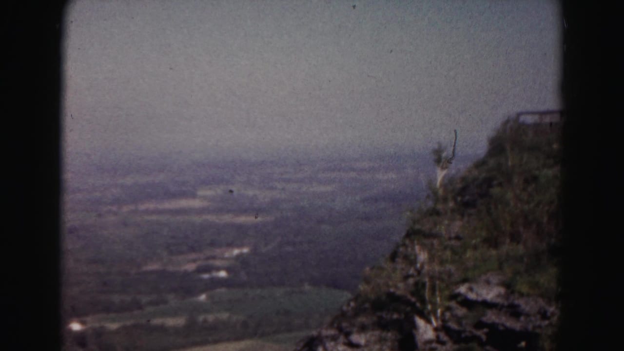 1963 8mm home-movie frame near Hagerstown showing a rocky overlook above a broad hazy valley.