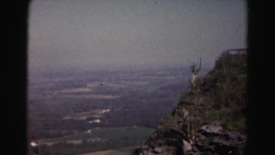 1963 8mm home-movie frame near Hagerstown showing a rocky overlook above a broad hazy valley.