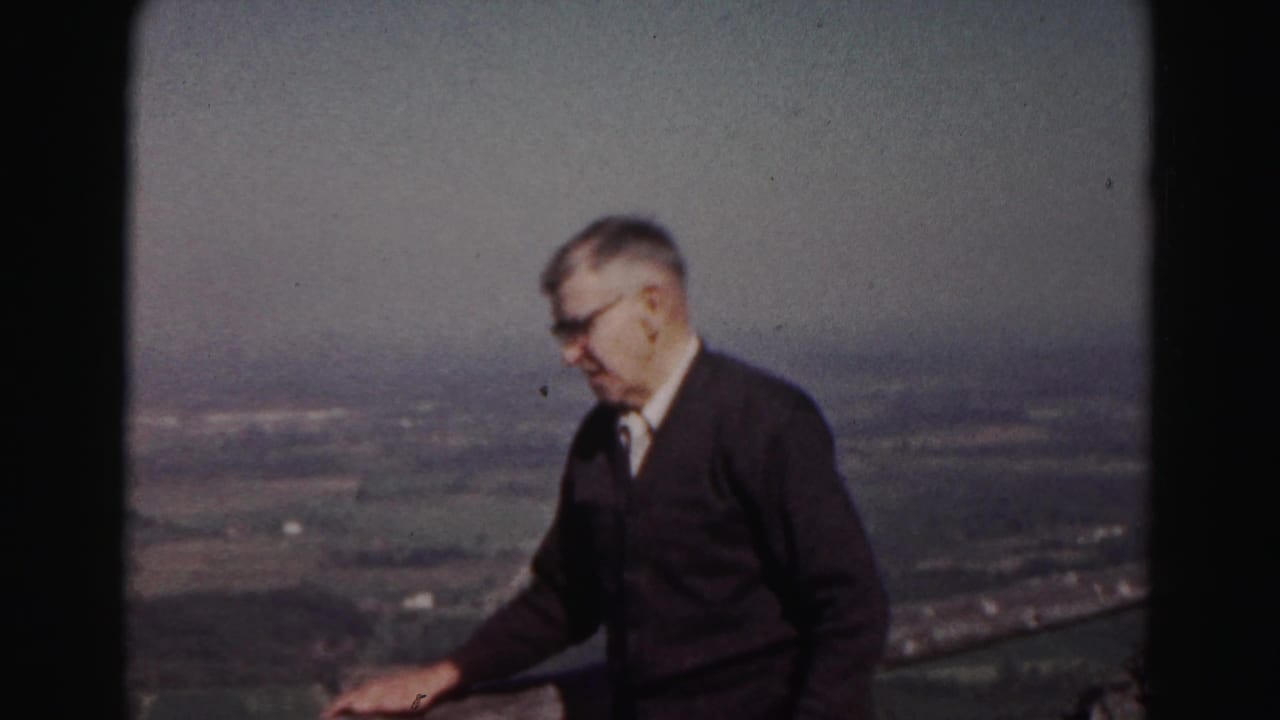 Older man in glasses and a dark sweater stands on a hilltop overlook near Hagerstown in 1963 home-movie footage.