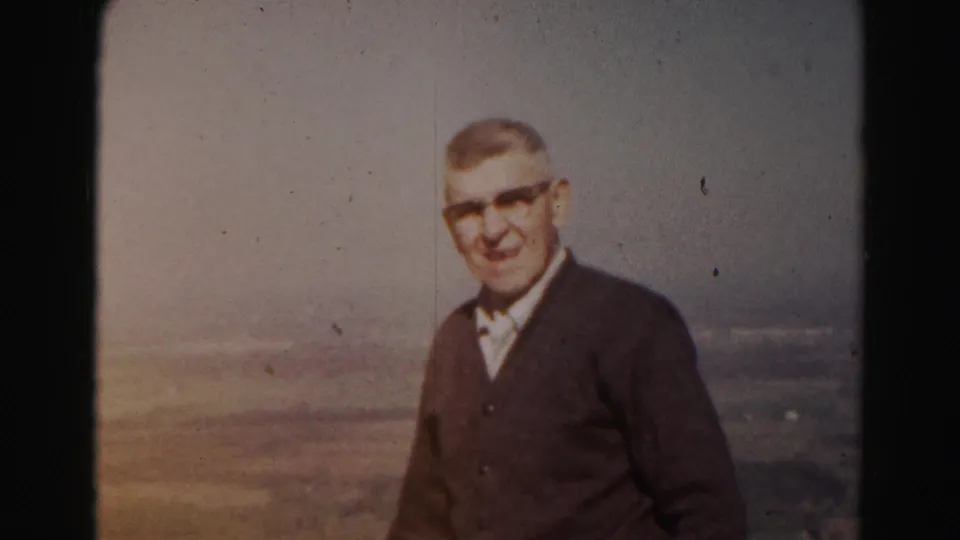 Older man in glasses faces the camera on a hilltop overlook in 1963 Hagerstown-area 8mm footage.