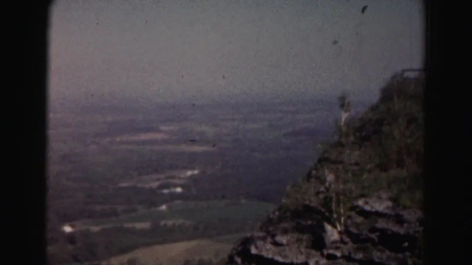 Final frame of the 1963 Maryland overlook clip, with a dark rocky edge at right and a hazy countryside panorama beyond.