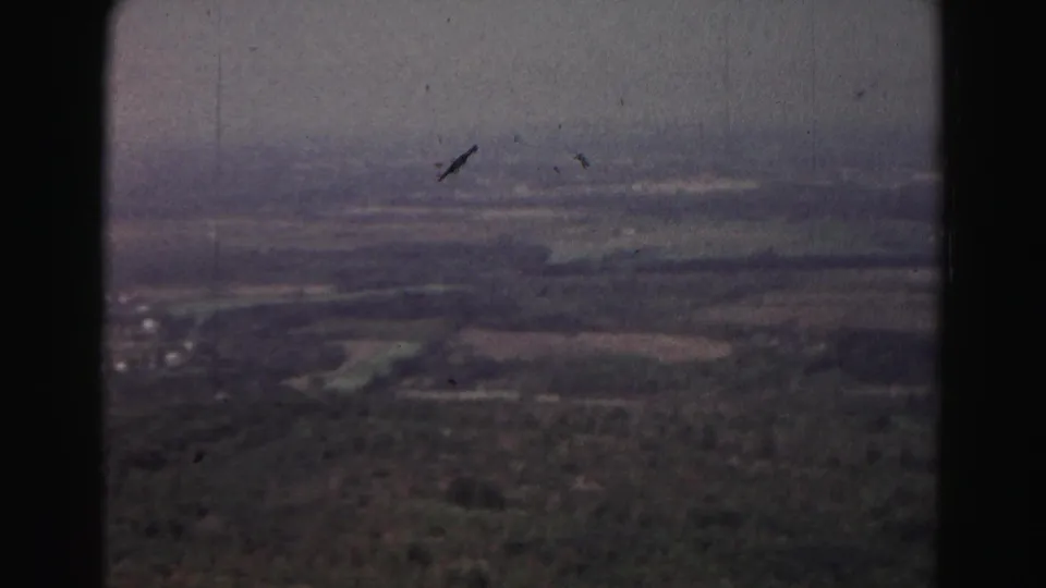 1963 Hagerstown-area aerial view showing patchwork fields, wooded areas, and a hazy horizon on 8mm film.