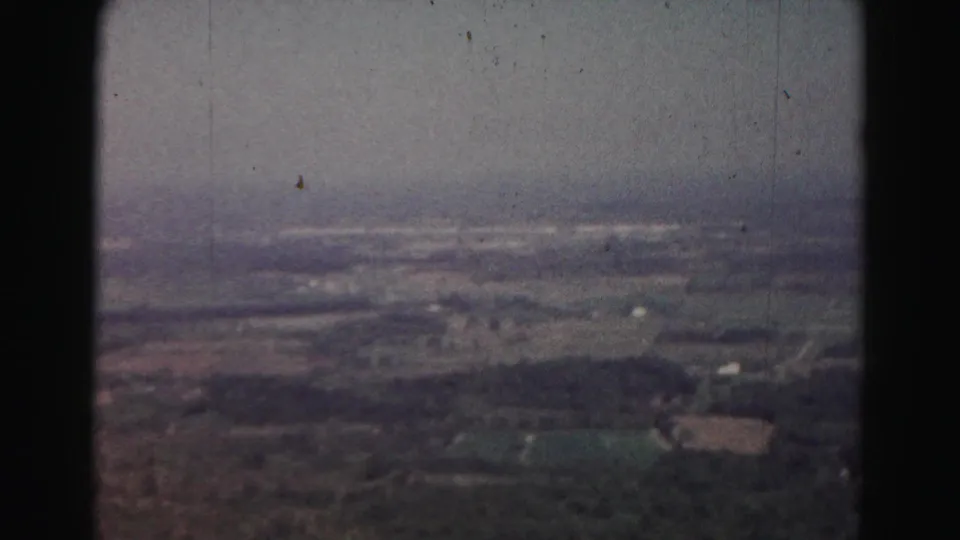 1963 Hagerstown-area aerial frame showing fields, tree cover, haze, and small distant rural structures.