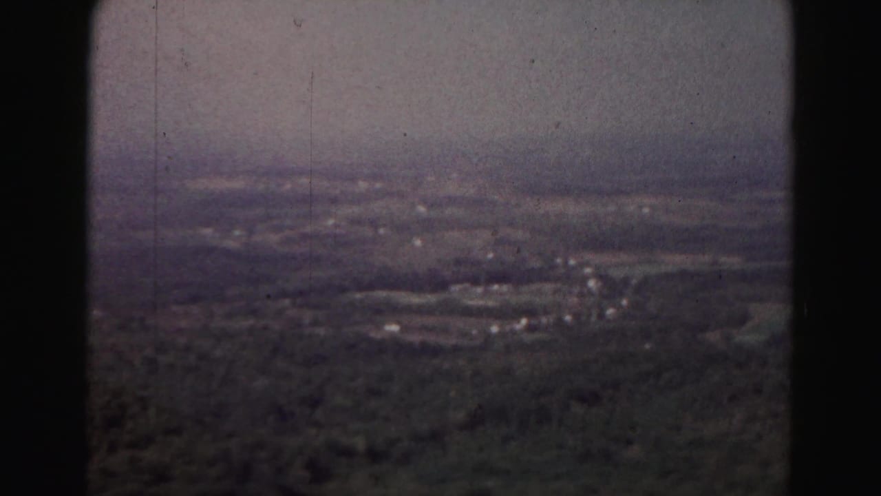 Elevated 1963 Hagerstown-area view across a hazy rural valley with wooded foreground, scattered buildings, fields, and pale sky.