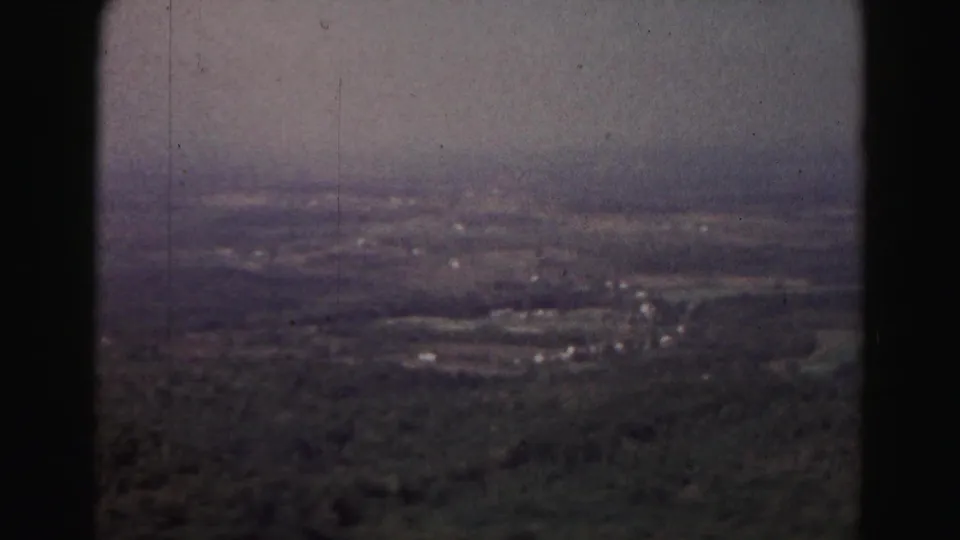 Elevated 1963 Hagerstown-area view across a hazy rural valley with wooded foreground, scattered buildings, fields, and pale sky.
