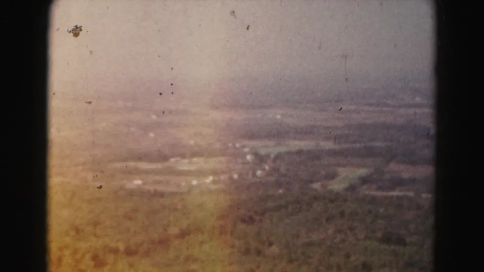 Soft 8mm frame of the Hagerstown-area rural panorama, with distant fields and buildings partly veiled by haze and a warm light flare.