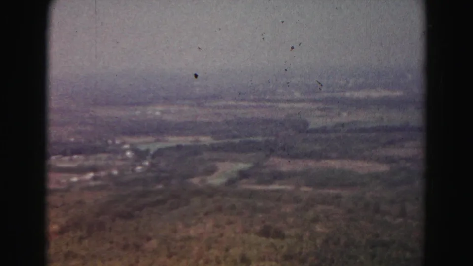 Final 1963 Hagerstown-area panorama frame showing wooded slopes, distant fields, scattered buildings, pale sky, and visible film dust.