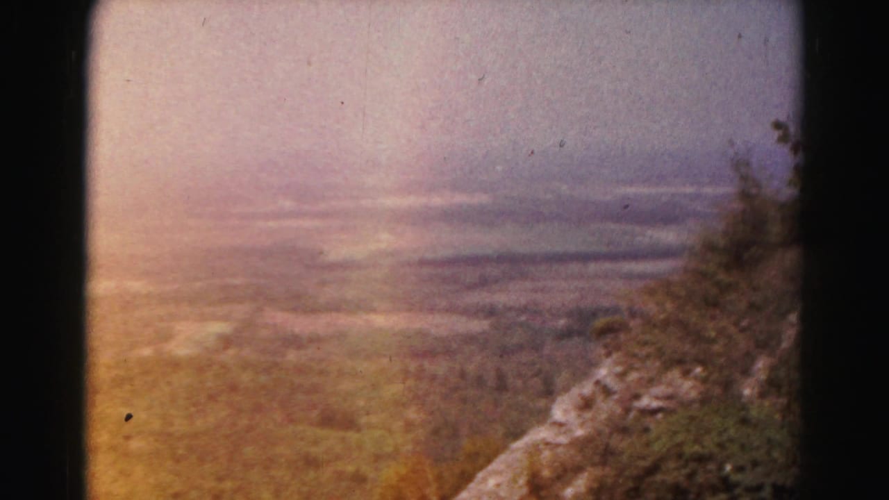Hazy valley seen from a wooded hillside with dark 8mm frame borders.