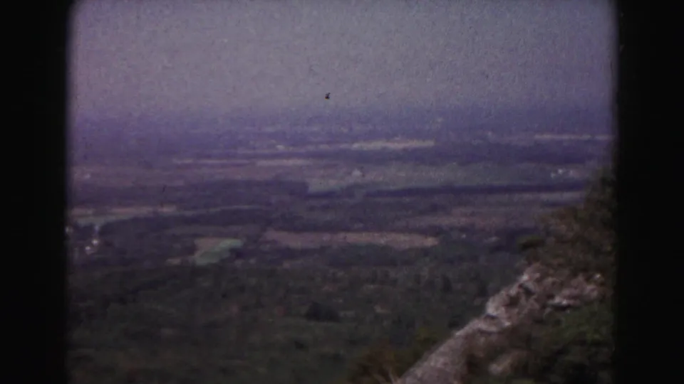 1963 Hagerstown-area view from a rocky overlook across wooded land, fields, and a hazy rural horizon.