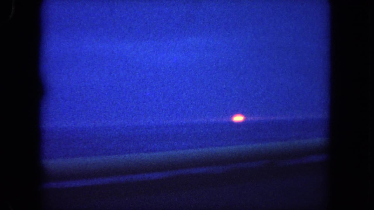 Orange sun glows above a dark ocean horizon in a blue-tinted dusk frame.
