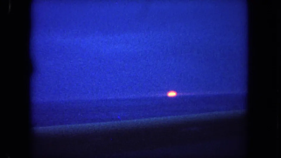 1962 Tijuana, Mexico 8mm frame showing a low orange sun against a blue dusk seascape and horizon line.