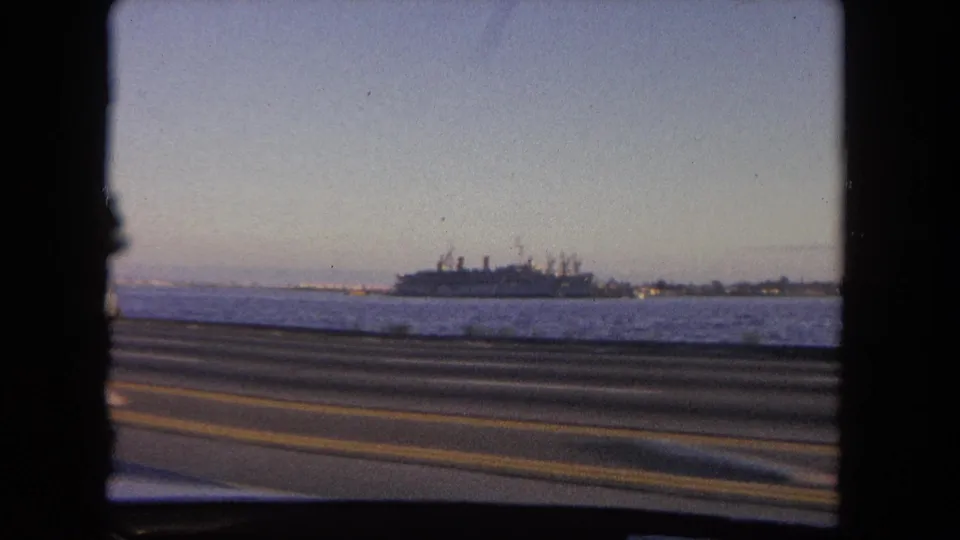 The final frame holds on the waterfront view near Tijuana, with a large ship across the water and highway lanes in the foreground.