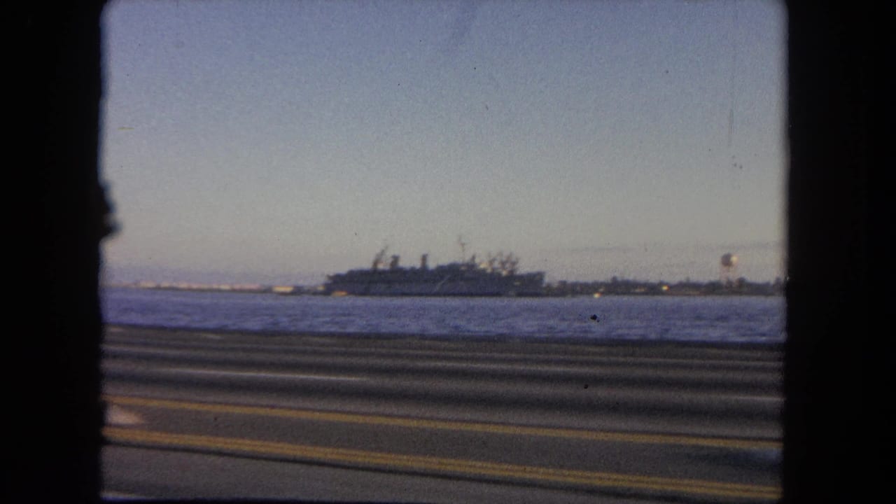 Coastal roadway and open water with a large ship near the shoreline.