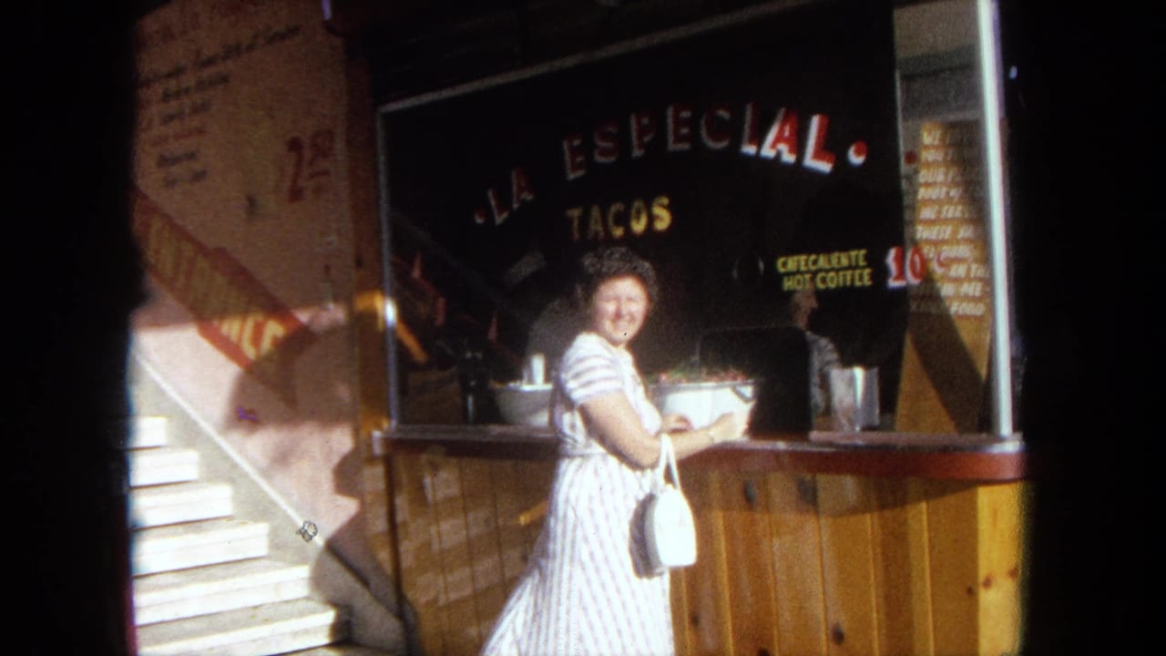 Woman in a striped dress smiles beside a taco stand counter with La Especial Tacos signage.