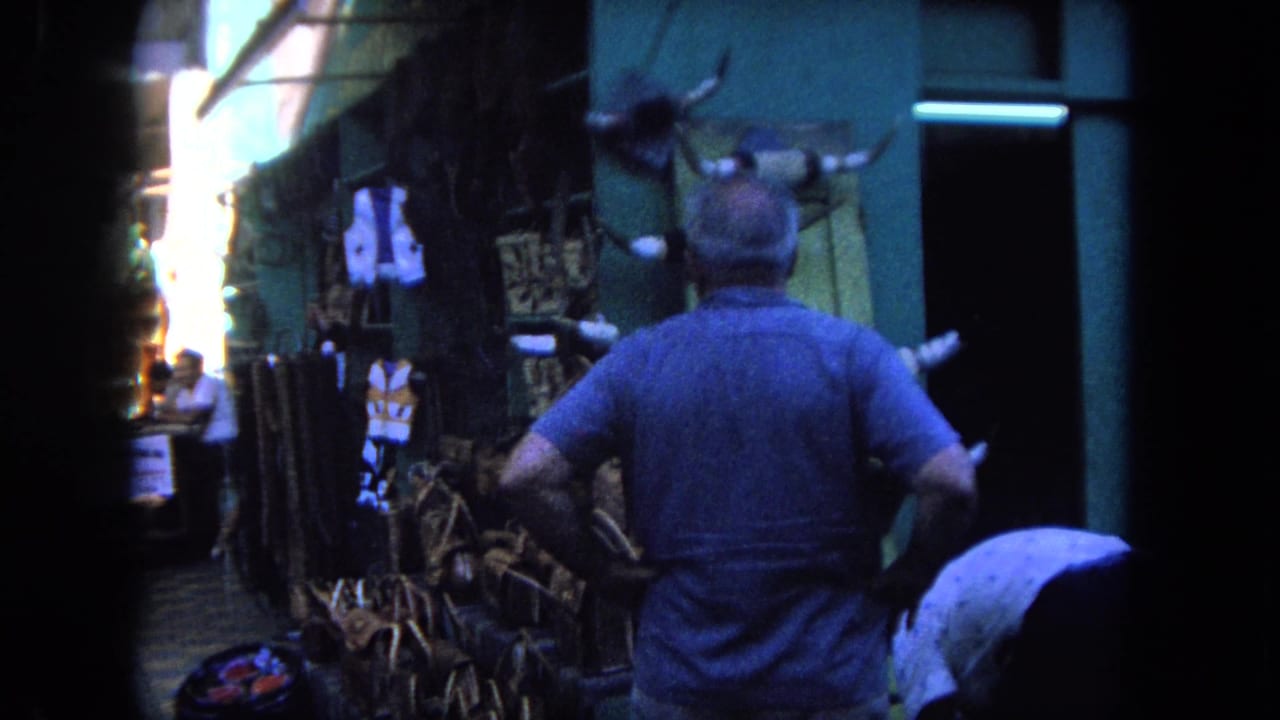 Man in a blue shirt faces a stall with horns and woven goods in a narrow market lane.