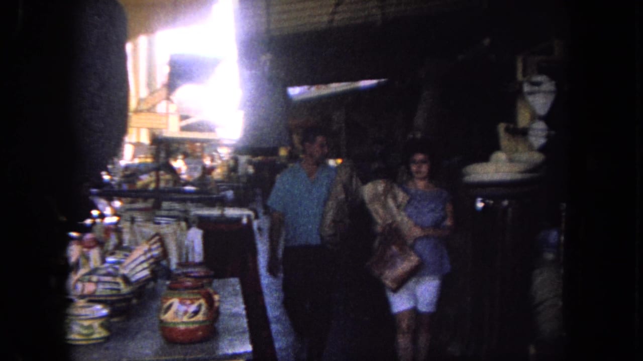 Couple walking through a market with pottery and goods on display.
