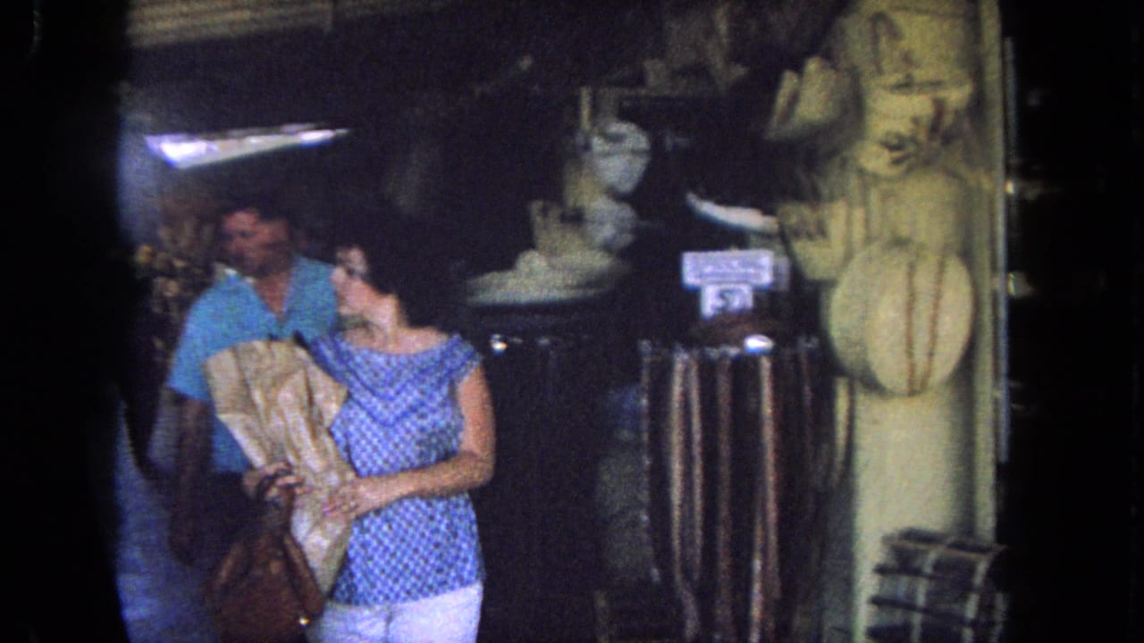 Woman carrying a wrapped purchase beside a man in a shop entrance.