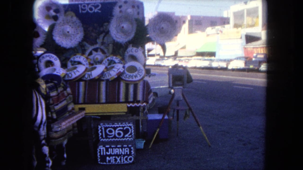 Decorated Tijuana cart with sombreros, a 1962 sign, and traffic behind it.