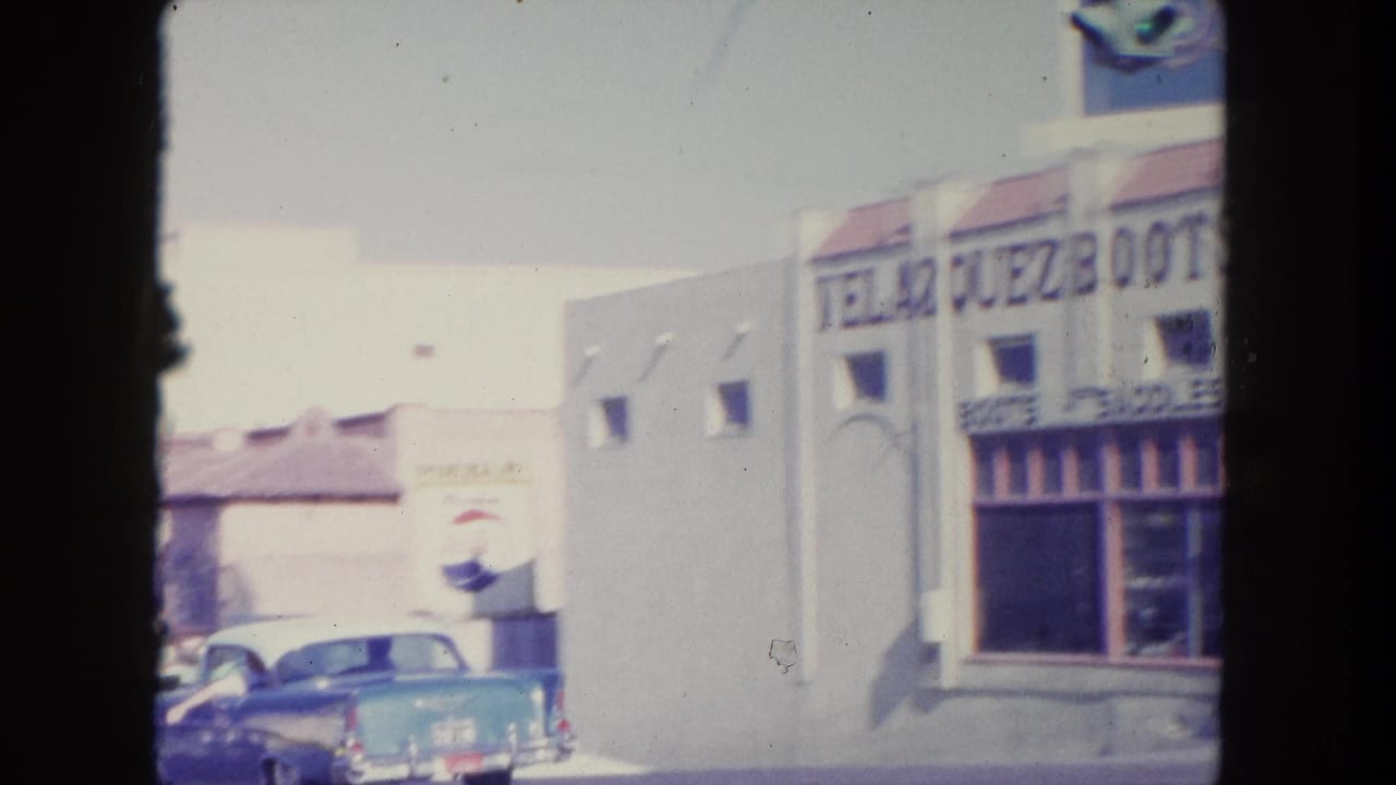 Downtown storefronts with a blue car parked along the street.