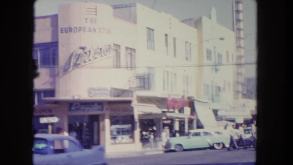 1962 Tijuana storefront view showing The European Store sign, parked classic cars, sidewalk pedestrians, awnings, and mid-century commercial buildings.