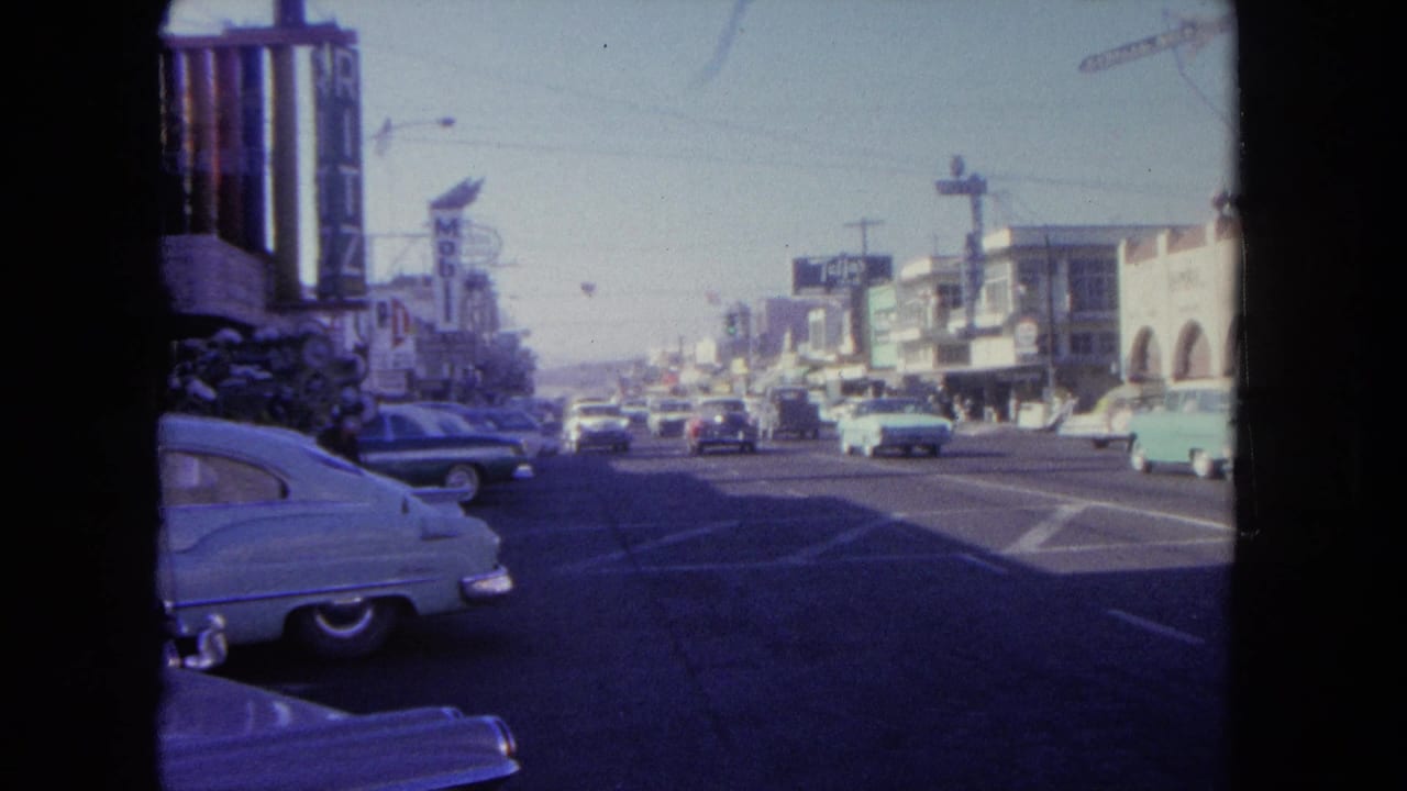 A 1962 Tijuana street scene shows classic cars, commercial buildings, vertical signs, and traffic under a bright sky.