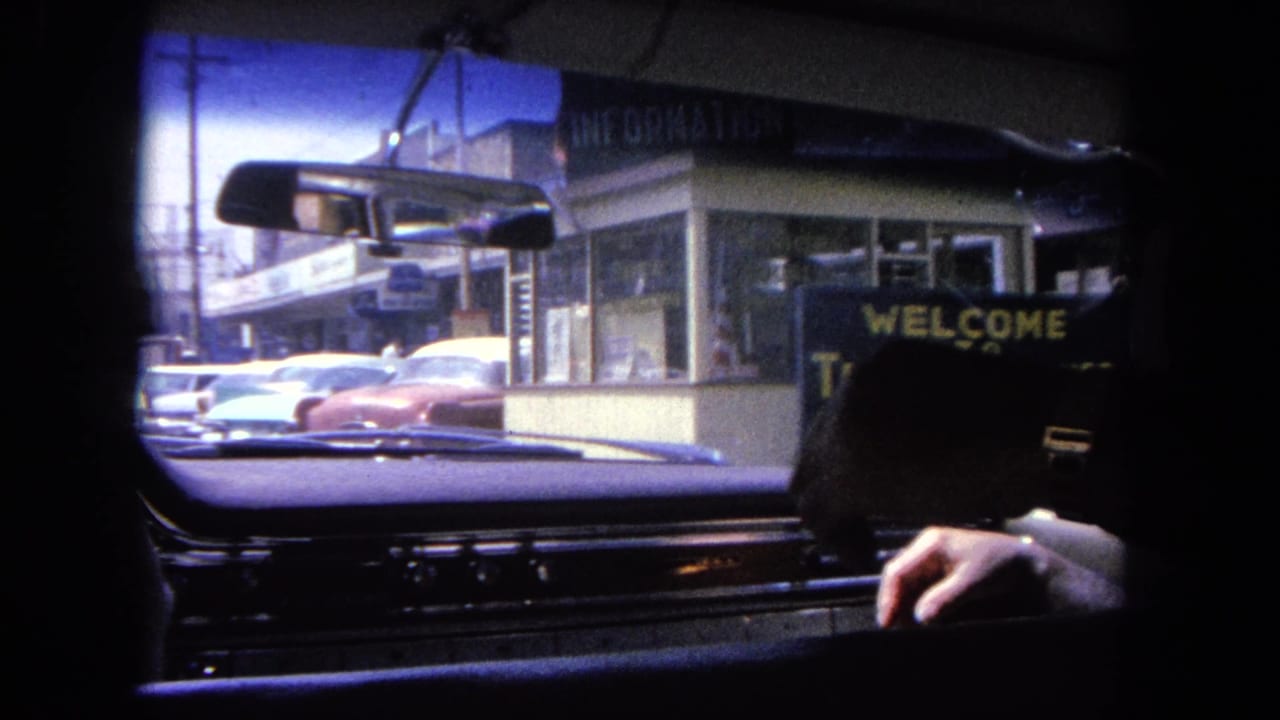 Passenger-side windshield view of a Tijuana welcome sign beside street traffic.