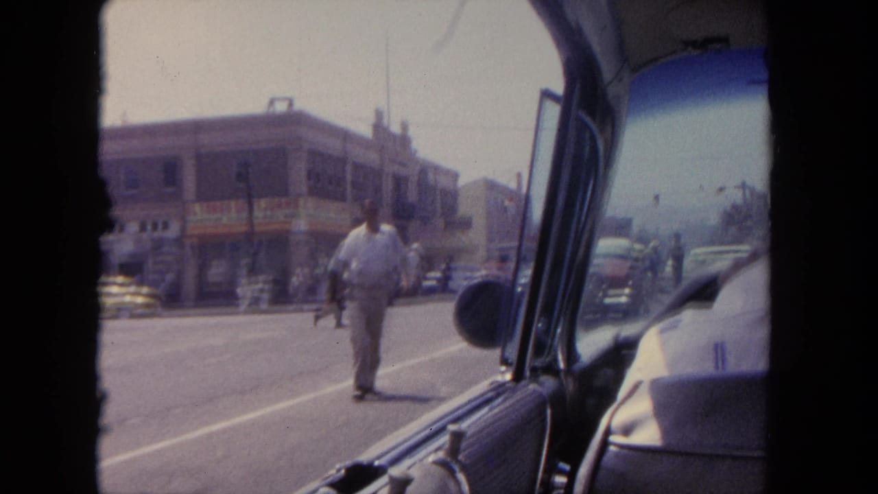 View from inside a car toward a Tijuana street corner as a man walks across the road.