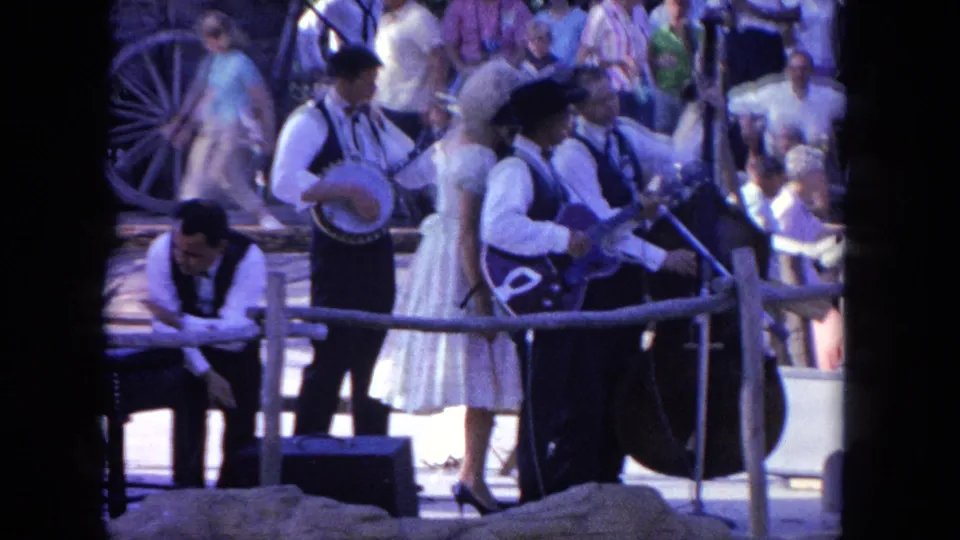 A 1962 Tijuana home-movie frame shows the band from behind a dark foreground obstruction, with instruments and onlookers visible.