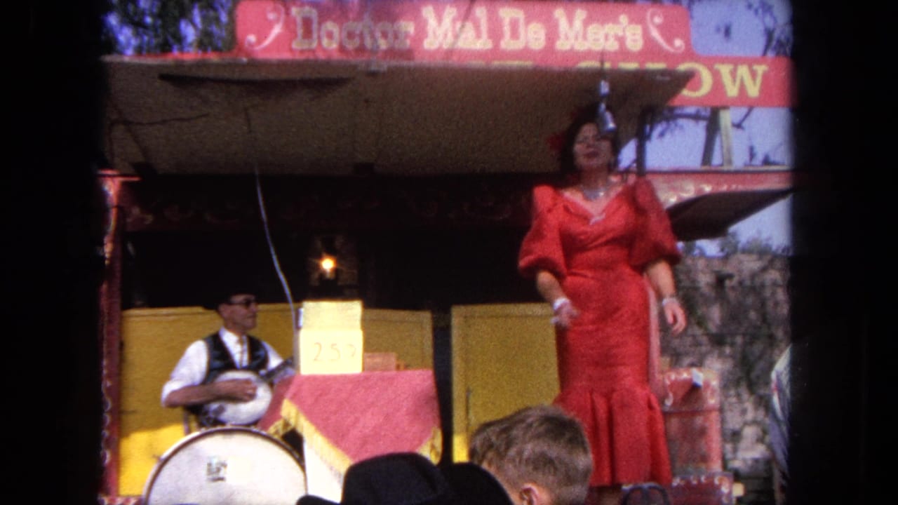 In 1962 Tijuana home-movie footage, a woman in a red dress performs on a carnival stage while a banjo player sits beside her.