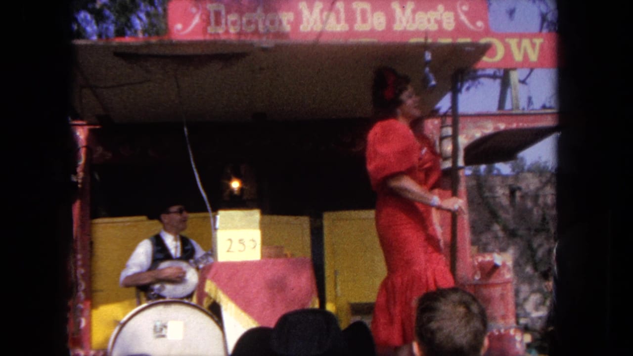 Woman in a red dress performs on a small stage while a musician sits beside a drum.