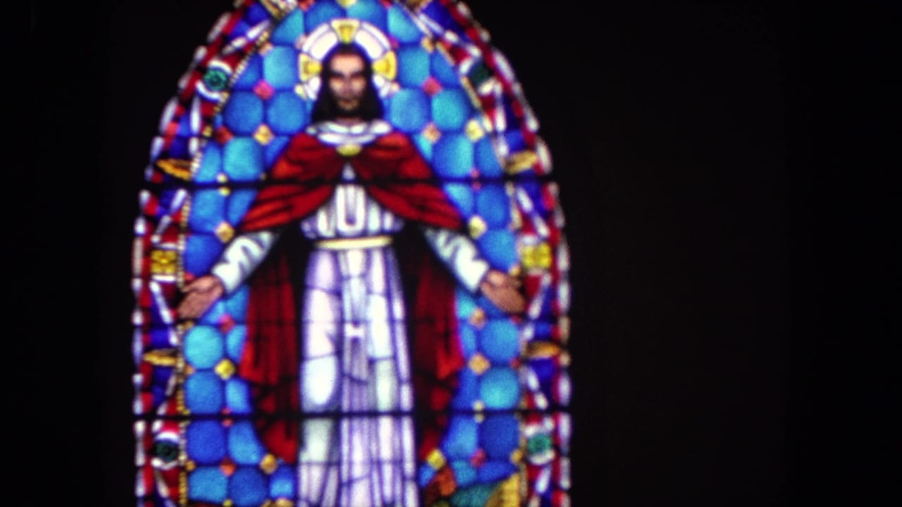 1962 Tijuana frame of an arched stained-glass window depicting Jesus with outstretched arms, red cloak, and blue patterned glass.