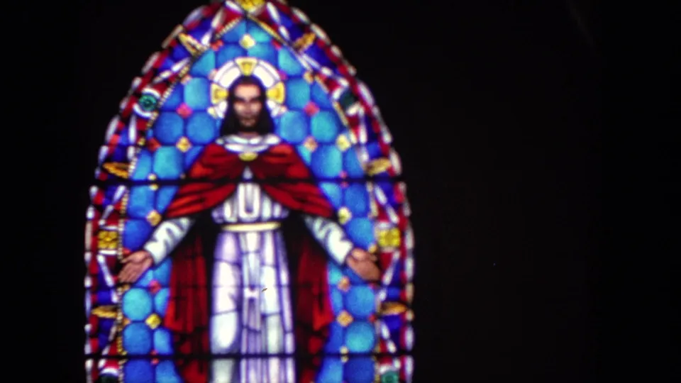 Final 1962 Tijuana frame holds on the stained-glass Jesus window, showing the arched design, blue background, red cloak, and white robe.