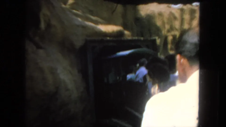 Rear passenger viewpoint from a 1962 San Diego tour train ride, with rockwork and a dark opening ahead.